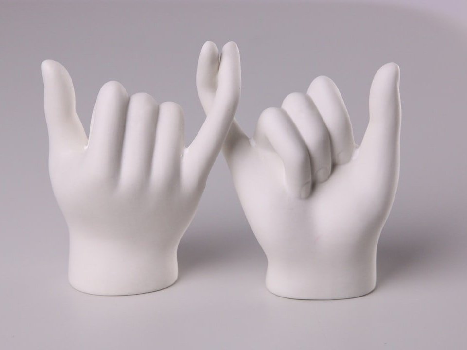 With their pinkies, two porcelain hand figures are gesturing "pinky promise."