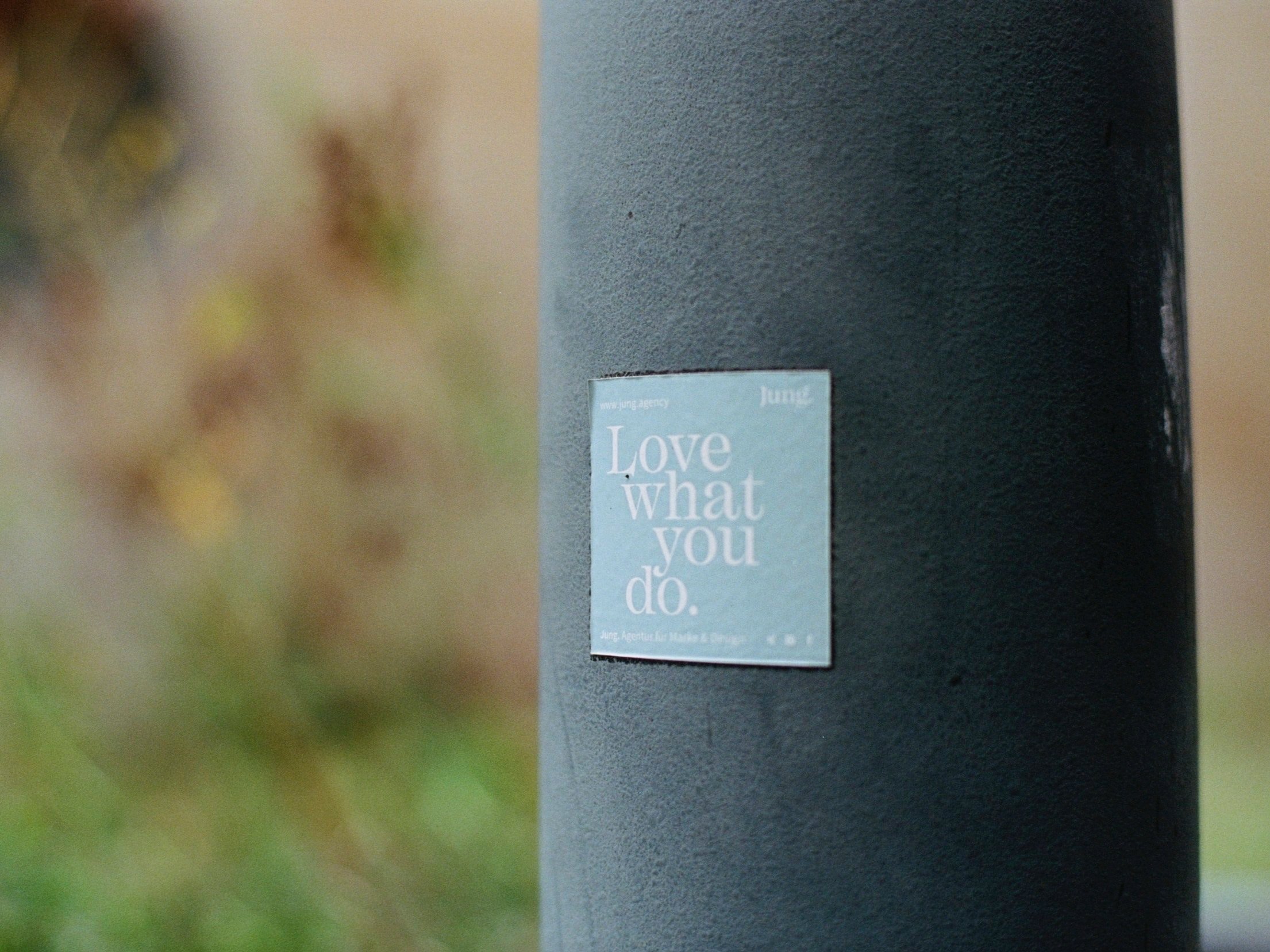 A sticker reading "Love what you do" is affixed to a painted concrete post.