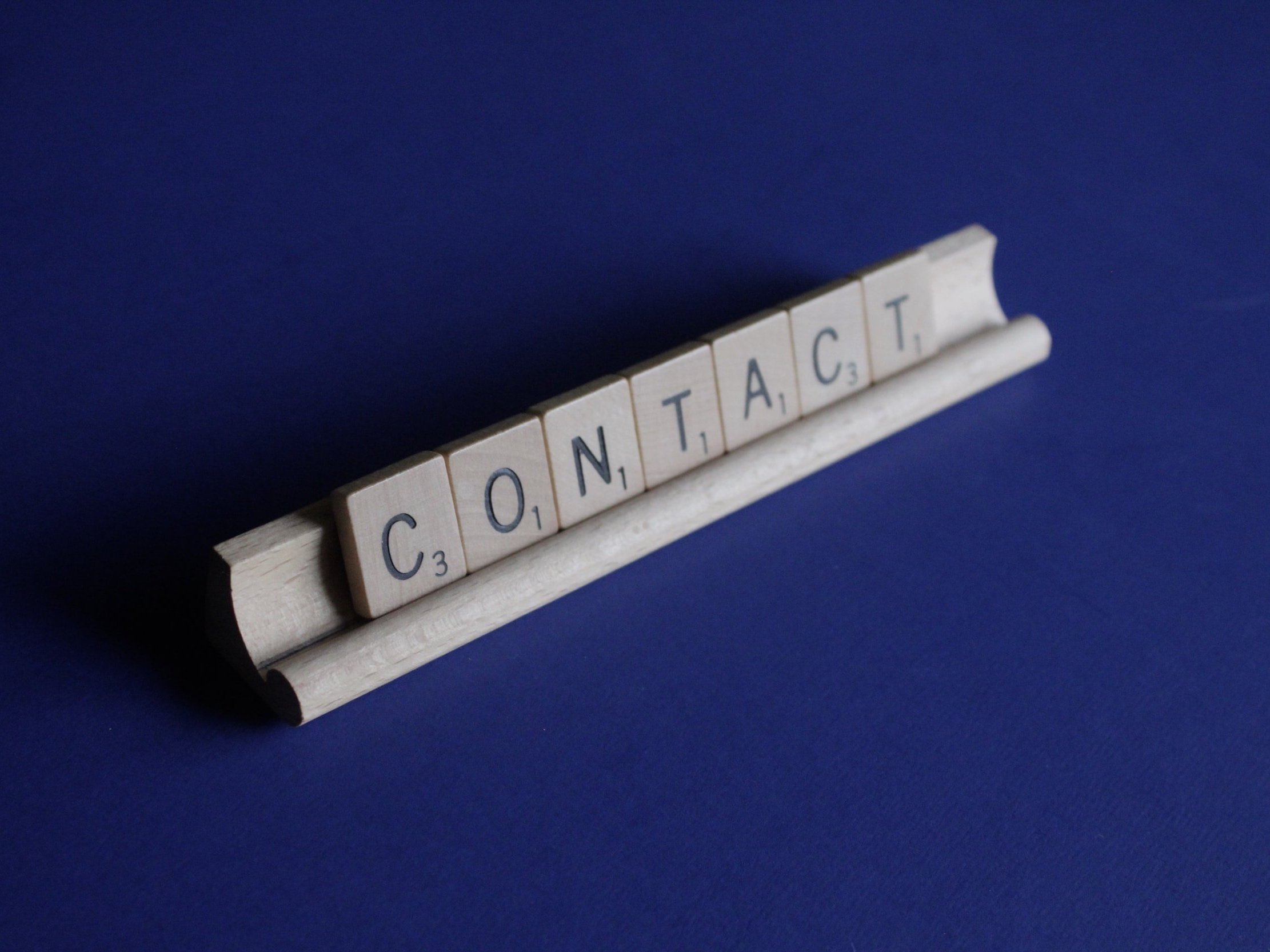 The word "Contact" is written in wooden alphabet tiles.