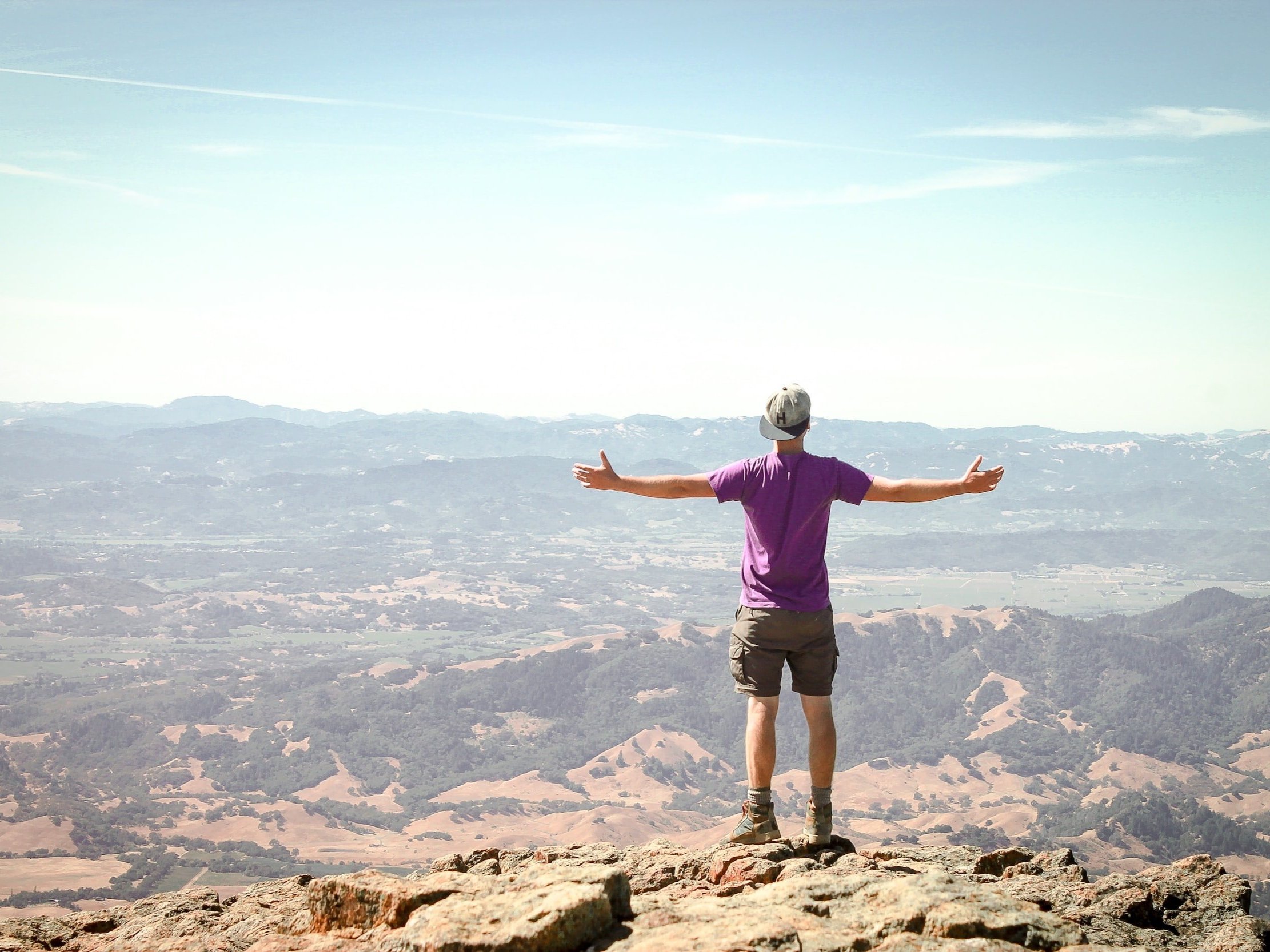 A man standing on top of a mountain, arms wide open