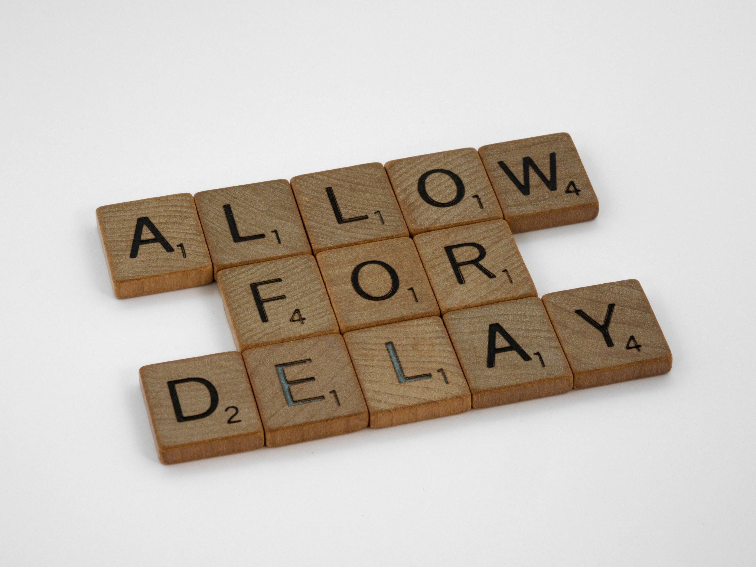 "Allow for Delay" is written in wooden letter tiles.
