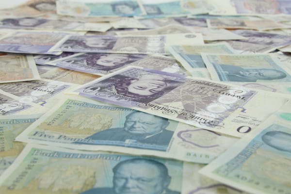 Assorted British banknotes spread out, showcasing different denominations and historical figures.