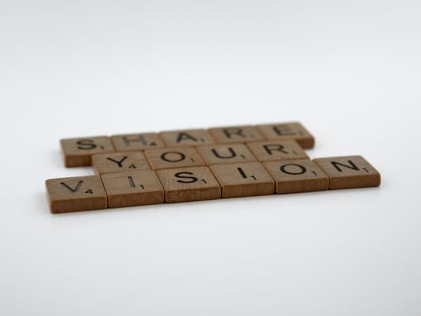 Scrabble tiles on a white background spell "SHARE YOUR VISION."
