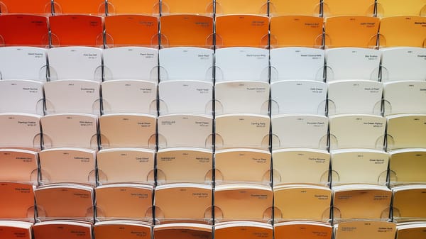 Wall of paint color samples ranging from white to orange, illustrating vast choice.