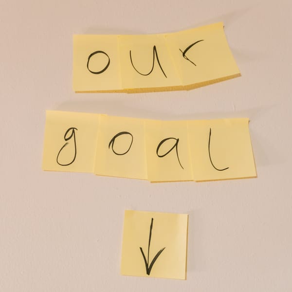 Sticky notes with handwritten letters spell out "goal", signifying goal-setting and having a clear purpose or objective.