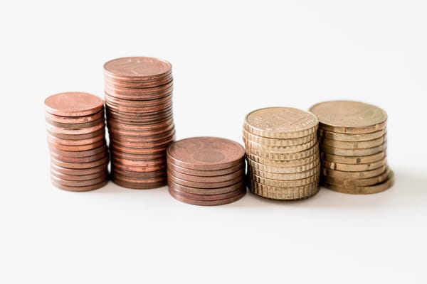 Stacks of pennies and other coins of various heights arranged in an abstract fashion on a plain white background.