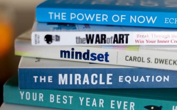 Stack of self-help books, including "Mindset" by Carol S. Dweck, focusing on personal growth.