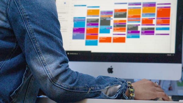 Person's jeans, calendar with colored blocks on screen - example of scheduling downtime for creativity to emerge.